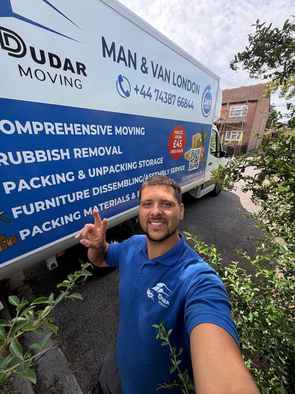 A Dudar Moving crew member in a branded polo shirt beside the liveried van