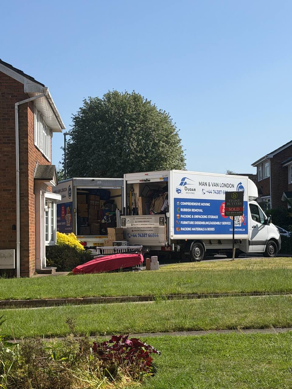 Two Dudar Moving vans loading outside a London house with a sold board